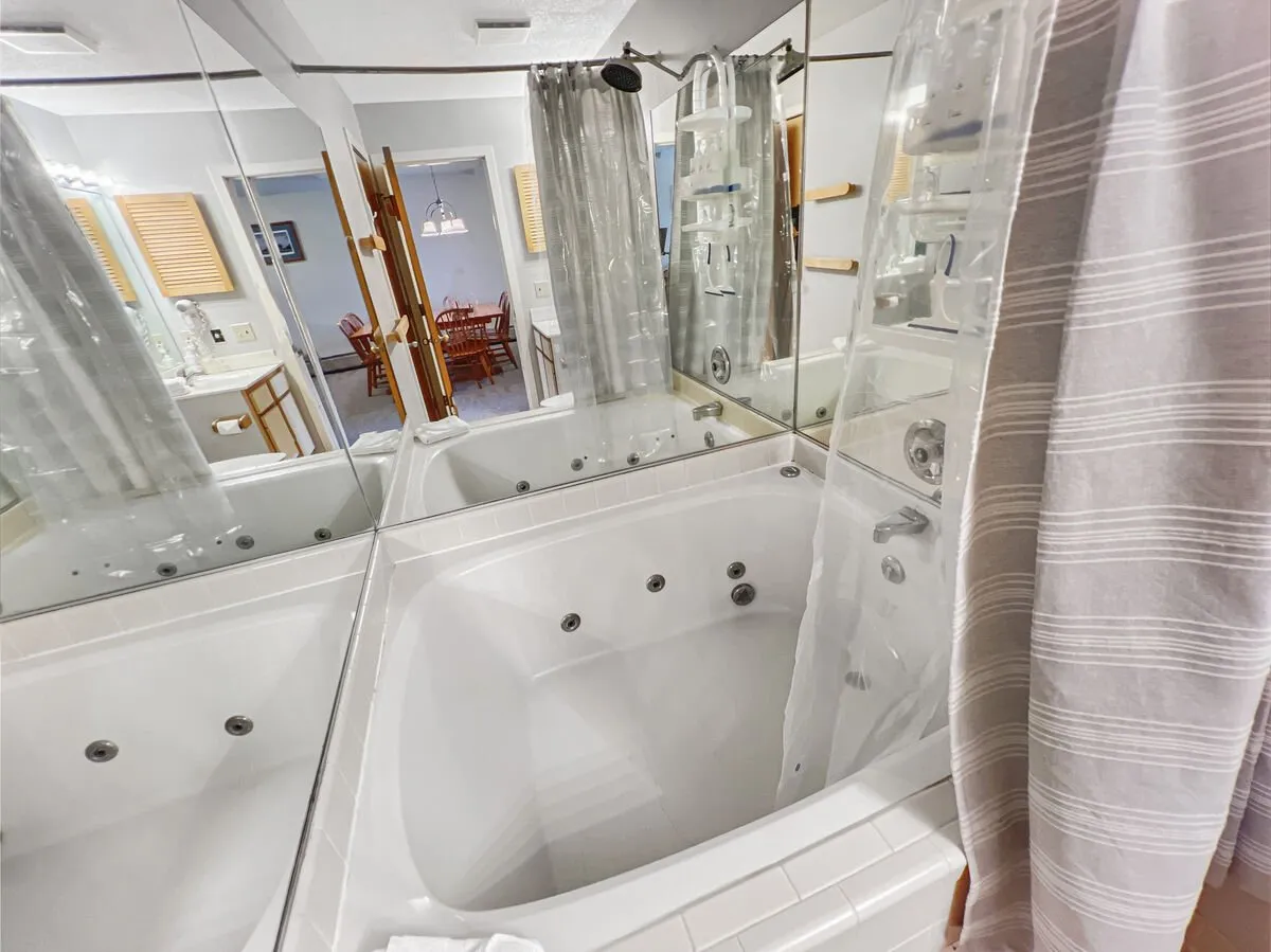A tranquil bathroom featuring a luxurious jacuzzi tub, mirrored walls, and a separate shower area. The spa-like ambiance invites relaxation and self-care after exhilarating outdoor activities.