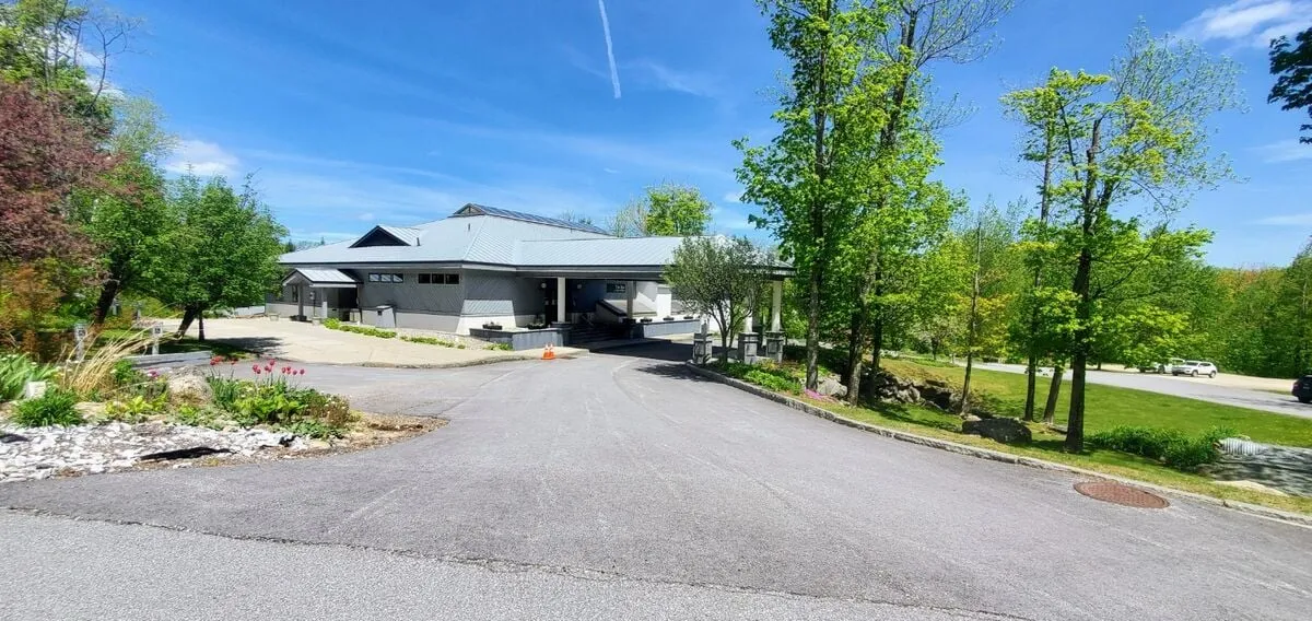 The property’s modern façade is complemented by a landscaped garden and a broad driveway, inviting groups to gather. The setting is idyllic, with greenery suggesting summer activities, morning coffees on the porch, and evenings spent socializing outdoors. The space feels both communal and private, perfect for group getaways across all seasons.