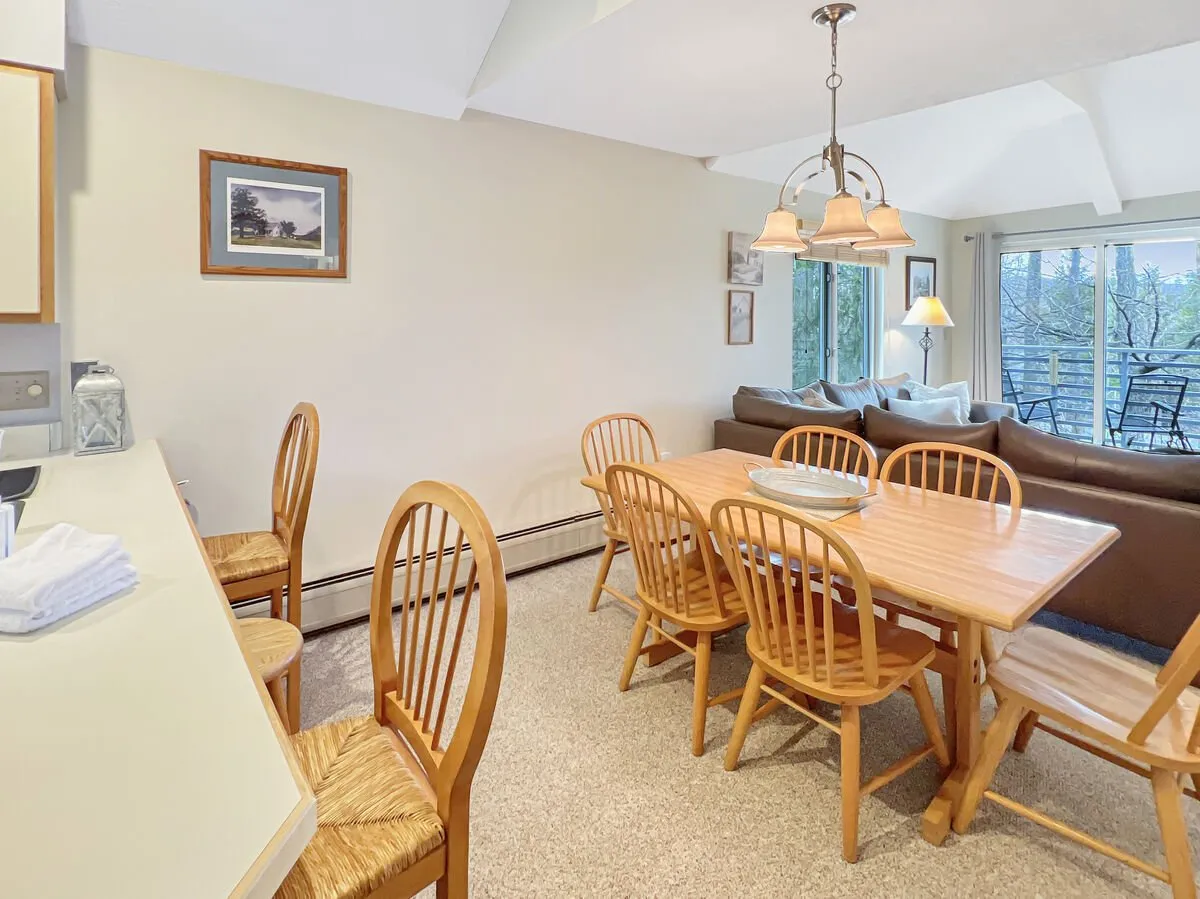 A comfortable and inviting interior view showing a dining table set for a meal, a cozy sofa nearby, and large windows offering a pleasant view outside. This communal space encourages relaxation, conversation, and shared moments.