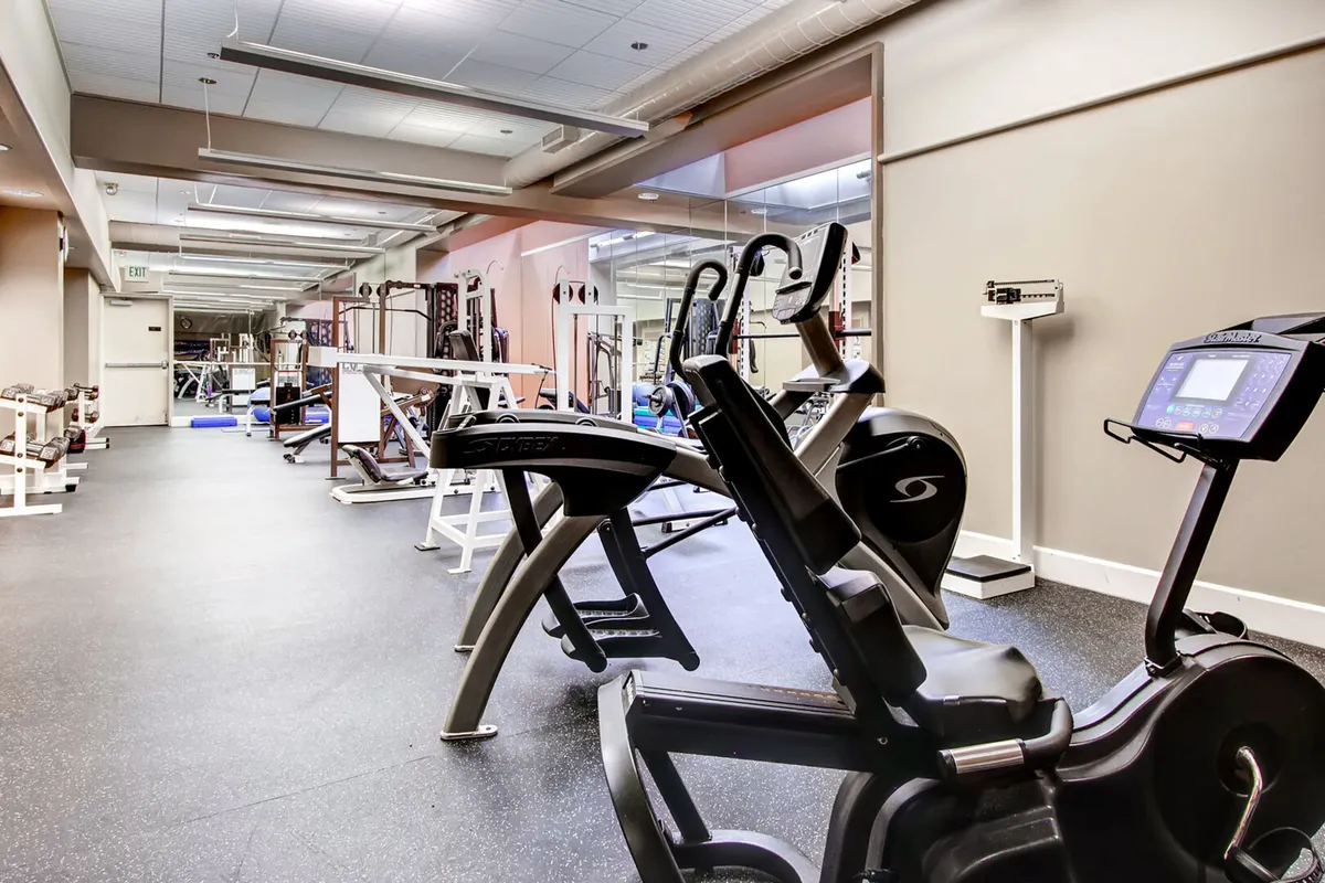A modern fitness center filled with exercise machines, mirrored walls for a bright and open feel, and a rack of free weights. The space is organized, clean, and designed to motivate guests to achieve their wellness goals through personal or group workouts.