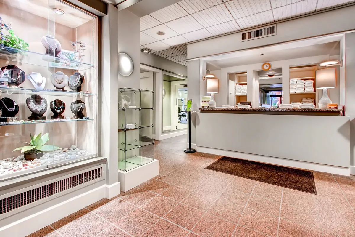 A luxurious spa reception area with neatly stacked towels, a jewelry display, and a welcoming reception desk. The mood is tranquil and indulgent, inviting you to check in for personalized spa treatments and unwind in a pampered setting.